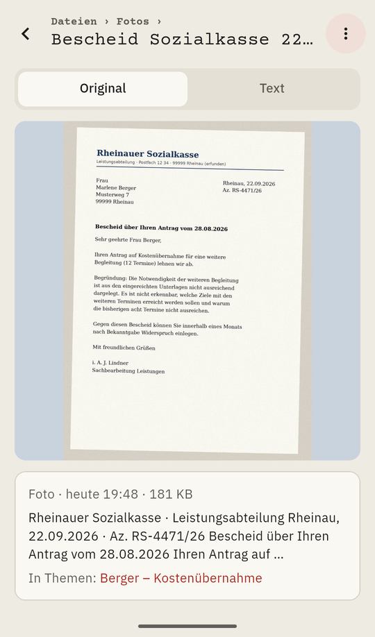 Das Foto des Bescheids geöffnet, darunter Absender, Datum und Aktenzeichen. Erfundene Daten.